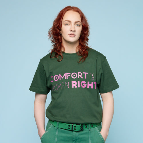 Person wearing a green Pride t-shirt with 'COMFORT IS RIGHT' text on a light blue background