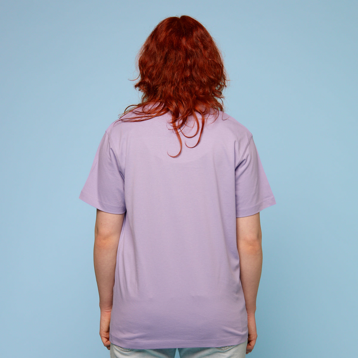 Person wearing a light purple t-shirt against a blue background - rear view