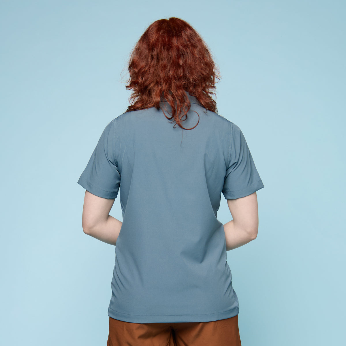 Person wearing a blue button up swim shirt with a collar - back view